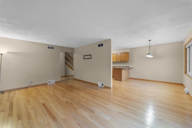 314 Castle Oaks Xing, Waunakee, WI 53597 - unfurnished living room featuring light wood finished floors, stairs, and baseboards