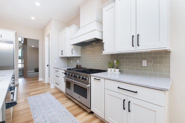 4779 Pine Meadows Ln, Hartland, WI 53029 - kitchen featuring white cabinetry, custom exhaust hood, range with two ovens, and light wood-type flooring
