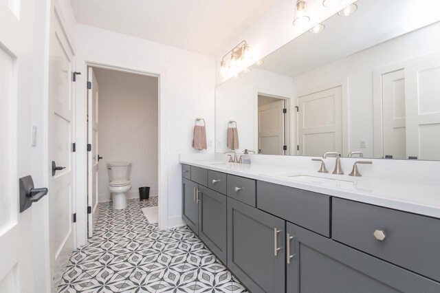 4779 Pine Meadows Ln, Hartland, WI 53029 - bathroom with double vanity, toilet, baseboards, and a sink