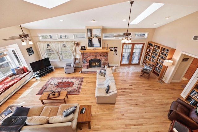6112 County Road A, Brooklyn, WI 53521 - living area featuring vaulted ceiling with skylight, light wood-style flooring, a ceiling fan, and a brick fireplace