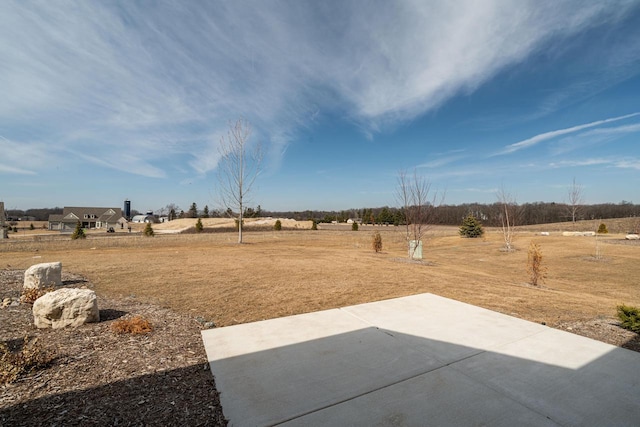 view of yard with a rural view and a patio area