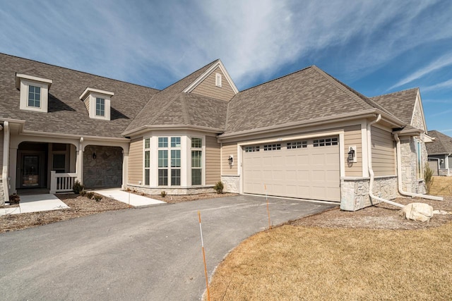 view of front of property featuring aphalt driveway, stone siding, a shingled roof, and a garage