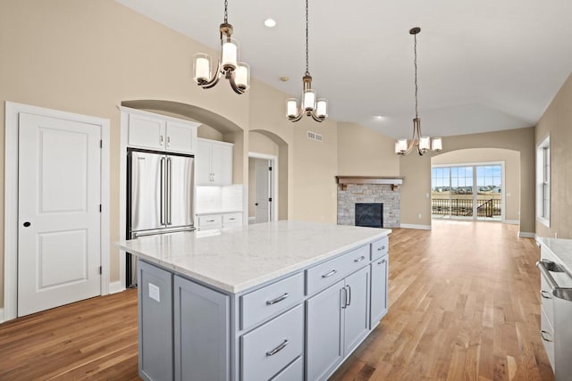 kitchen featuring vaulted ceiling, a kitchen island, high end fridge, and a chandelier