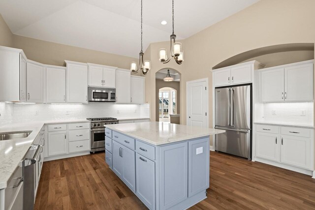 kitchen with vaulted ceiling, high end appliances, arched walkways, and a sink