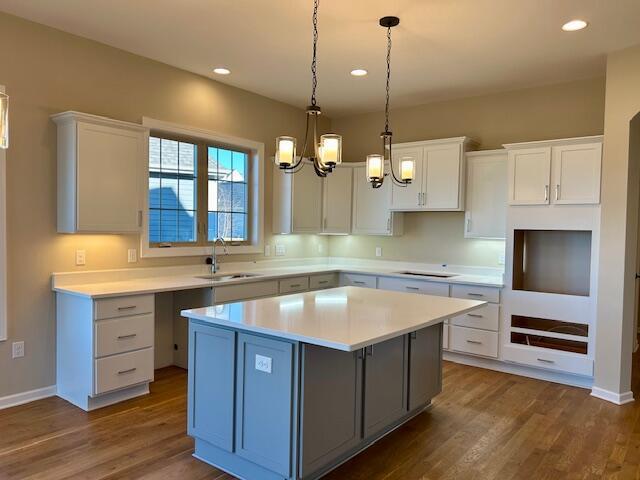 kitchen with dark wood finished floors, a kitchen island, stovetop, and a sink