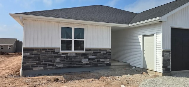2023 Red Fox Ln, Kaukauna, WI 54130 - view of property exterior featuring roof with shingles, stone siding, and a garage