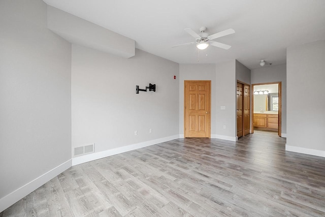 unfurnished room featuring wood finished floors, a ceiling fan, visible vents, and baseboards