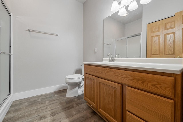 bathroom with baseboards, toilet, a stall shower, wood finished floors, and vanity