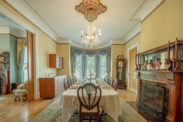 1222 11th St, Monroe, WI 53566 - dining space with a chandelier, light wood finished floors, a fireplace, ornamental molding, and baseboards