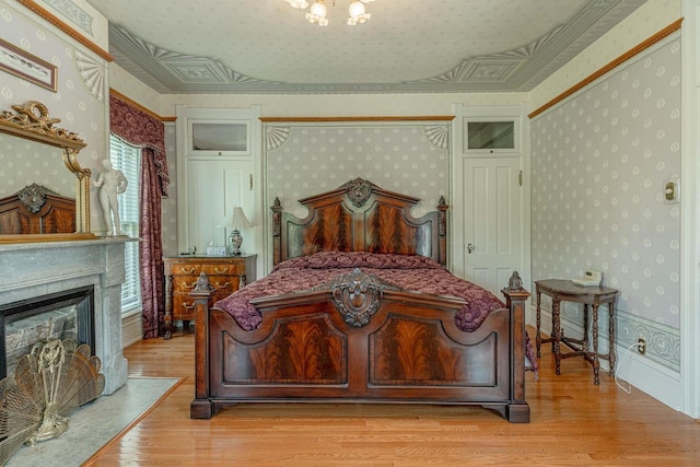 1222 11th St, Monroe, WI 53566 - bedroom featuring wallpapered walls, light wood-style flooring, and a glass covered fireplace