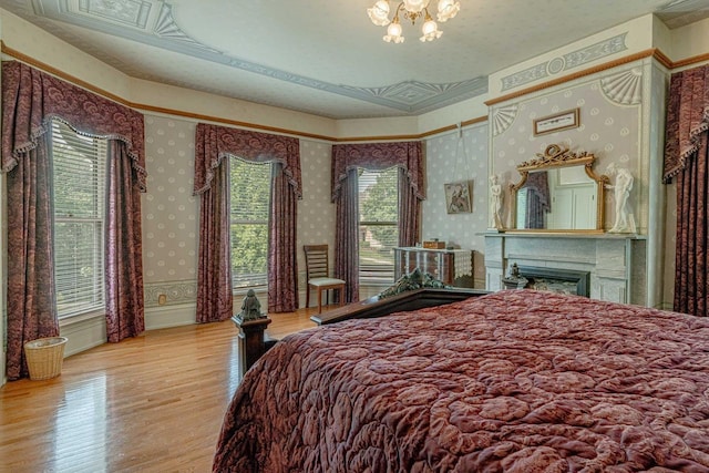 1222 11th St, Monroe, WI 53566 - bedroom featuring wallpapered walls, wood finished floors, a fireplace, and a chandelier