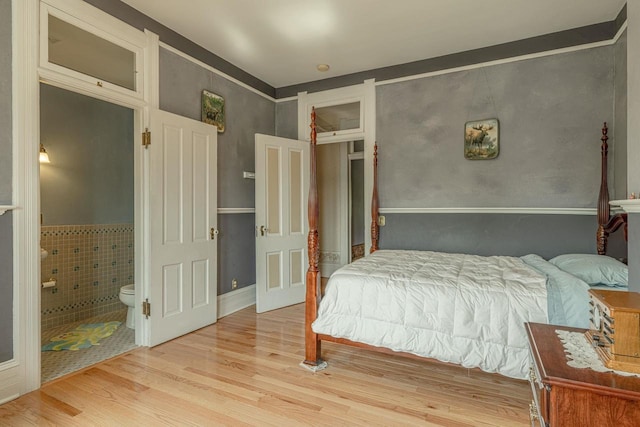 1222 11th St, Monroe, WI 53566 - bedroom featuring wood finished floors, connected bathroom, and wainscoting