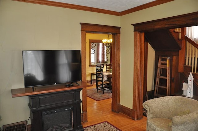 13600 8th St, Osseo, WI 54758 - living area featuring stairway, a glass covered fireplace, ornamental molding, wood finished floors, and a notable chandelier