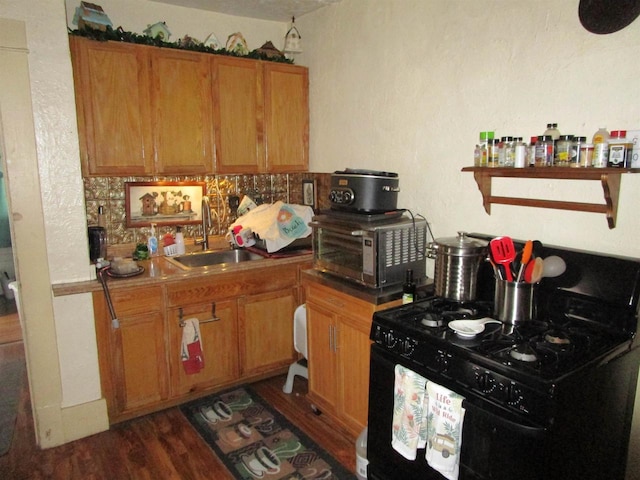 454 Center St, Adams, WI 53910 - kitchen featuring black range with gas stovetop, a sink, dark wood-style floors, brown cabinetry, and decorative backsplash