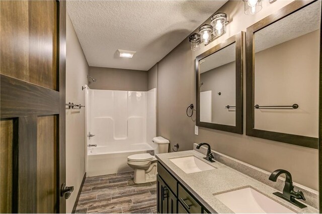 191 Pintail St, Baldwin, WI 54002 - full bath featuring a textured ceiling, wood tiled floor, toilet, and a sink