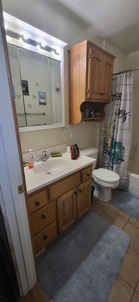 1116 Washington Ave, Stevens Point, WI 54481 - bathroom with shower / bathtub combination with curtain, toilet, tile patterned floors, and vanity