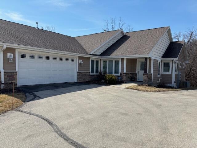 view of front of house featuring driveway, an attached garage, and stone siding