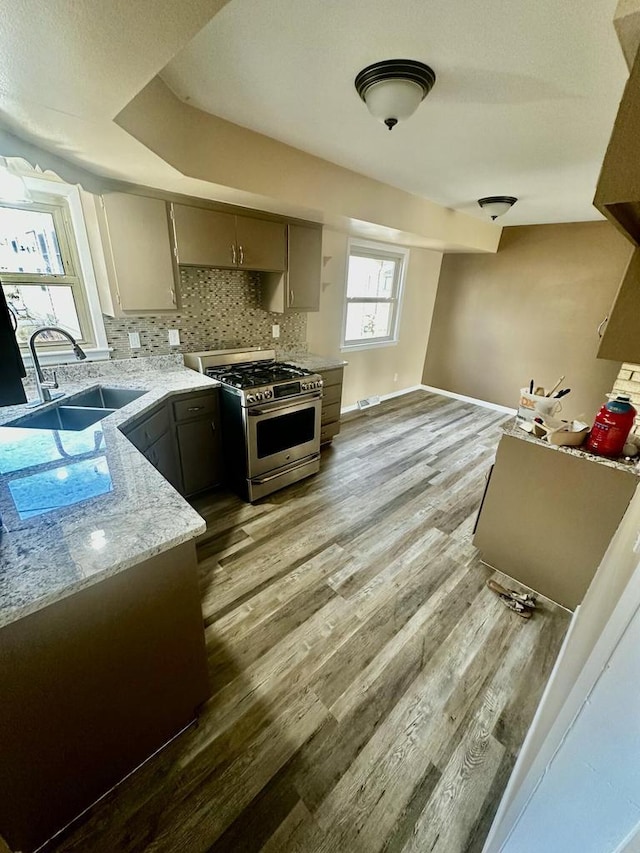 7140 N 48th St, Milwaukee, WI 53223 - kitchen featuring baseboards, light wood-type flooring, backsplash, stainless steel gas stove, and a sink
