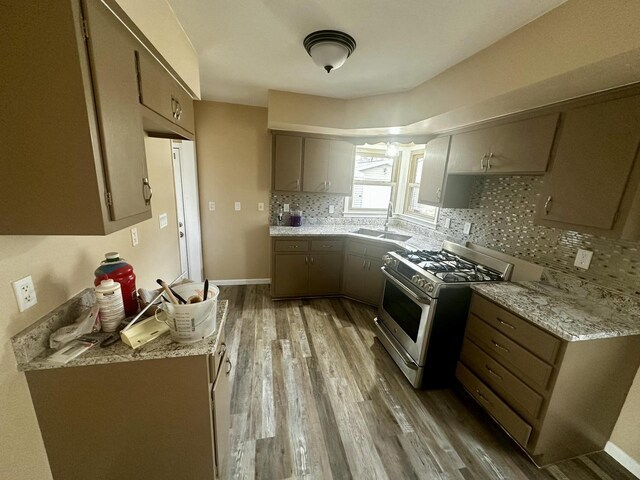 7140 N 48th St, Milwaukee, WI 53223 - kitchen with tasteful backsplash, stainless steel range with gas stovetop, a sink, light wood-style floors, and light stone countertops