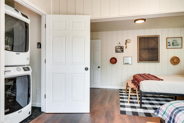 bedroom with dark wood finished floors, baseboards, and stacked washer / drying machine