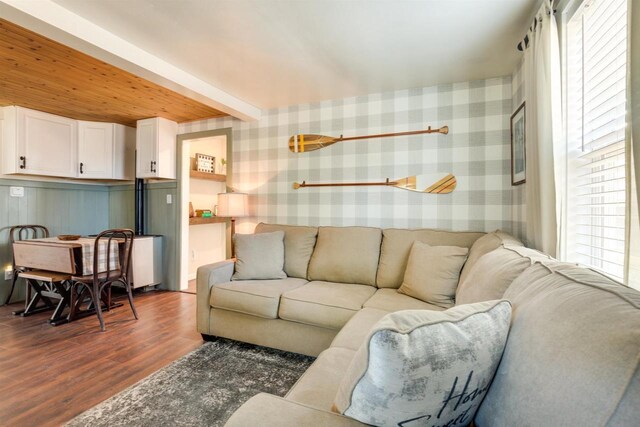 living room with wallpapered walls, plenty of natural light, and dark wood-style floors