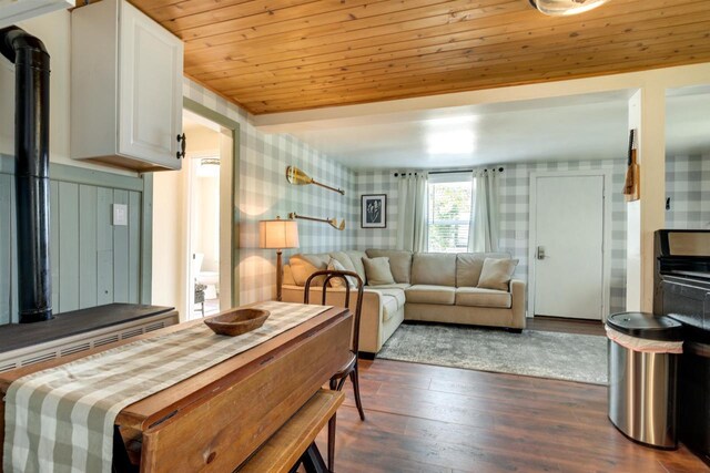 dining area with wallpapered walls, wooden ceiling, a wood stove, and dark wood-style flooring