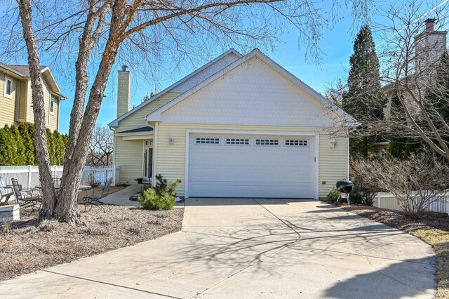 N8512 Booth Lake Heights Rd, East Troy, WI 53120 - view of front of house with an attached garage, a chimney, fence, and concrete driveway