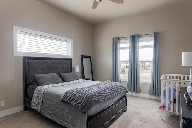bedroom featuring light carpet, a ceiling fan, and baseboards