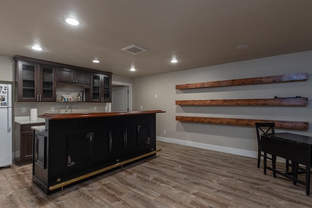 indoor wet bar featuring freestanding refrigerator, wood finished floors, recessed lighting, and baseboards