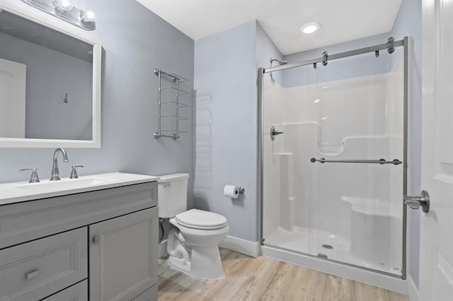 full bath with wood finished floors, a stall shower, toilet, and vanity
