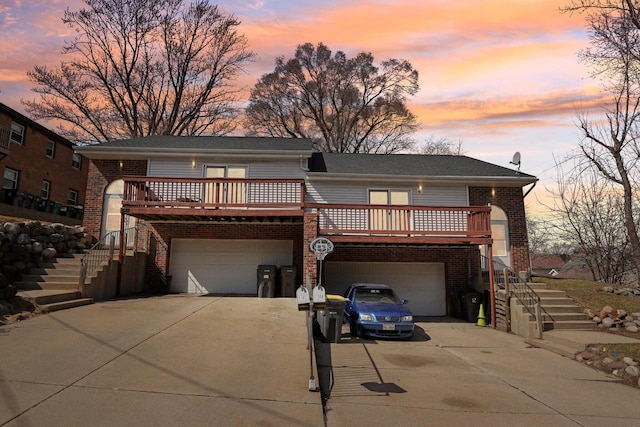 view of front of house featuring stairs, a garage, concrete driveway, and brick siding
