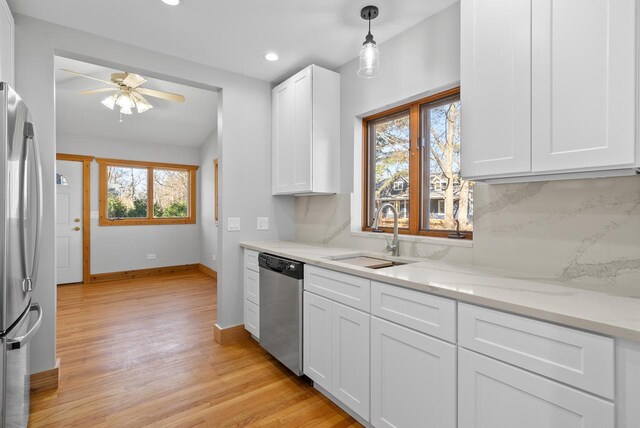 556 Highland Rd, Williams Bay, WI 53191 - kitchen featuring stainless steel appliances, a sink, a ceiling fan, baseboards, and white cabinetry