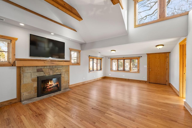 556 Highland Rd, Williams Bay, WI 53191 - unfurnished living room featuring a stone fireplace, high vaulted ceiling, light wood-style floors, healthy amount of natural light, and beamed ceiling