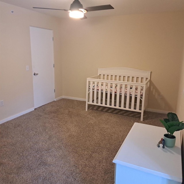 unfurnished bedroom with baseboards, ceiling fan, a crib, and carpet floors