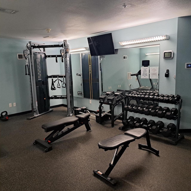 exercise room featuring baseboards, a textured ceiling, and visible vents