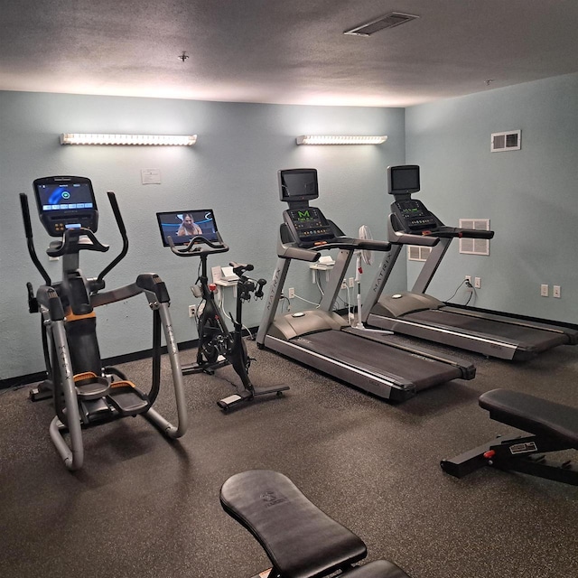 workout area featuring a textured ceiling, baseboards, and visible vents