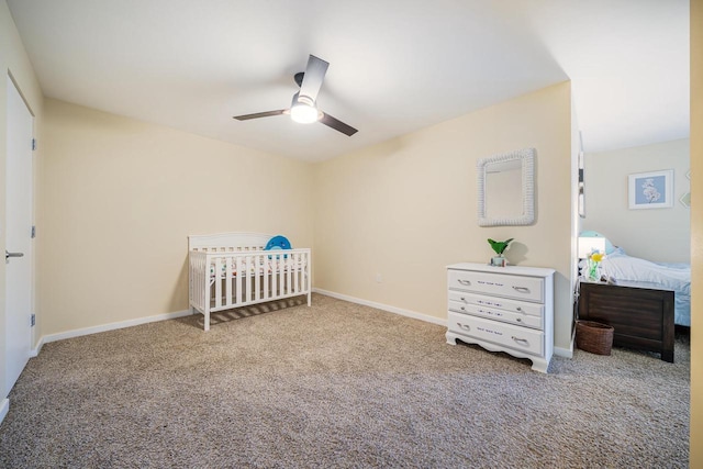 bedroom featuring carpet floors, a nursery area, baseboards, and ceiling fan