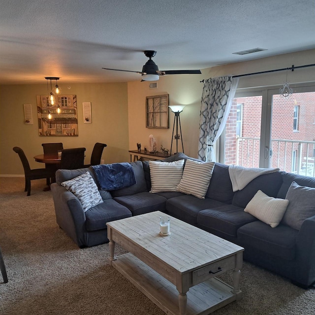 carpeted living room featuring a textured ceiling, ceiling fan, and visible vents