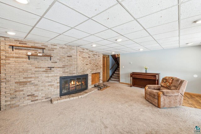 2507 Junction Rd, Ashland, WI 54806 - unfurnished room featuring a brick fireplace, carpet floors, stairway, and a drop ceiling