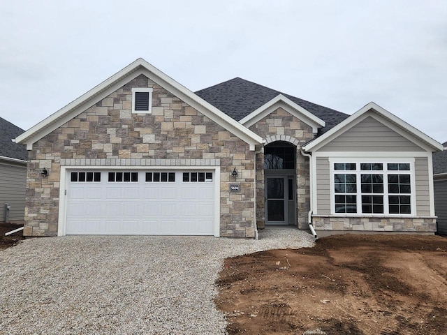 5684 N Kestrel Cir, Appleton, WI 54913 - view of front of property featuring stone siding, an attached garage, a shingled roof, and gravel driveway