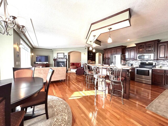 25621 Honeycut Ave, Tomah, WI 54660 - dining space featuring a textured ceiling, ornamental molding, wood finished floors, arched walkways, and an inviting chandelier