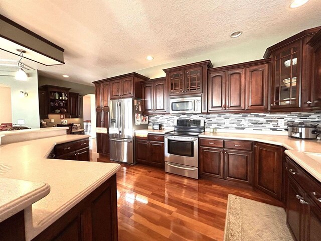 25621 Honeycut Ave, Tomah, WI 54660 - kitchen featuring light countertops, dark brown cabinetry, dark wood-style floors, glass insert cabinets, and stainless steel appliances