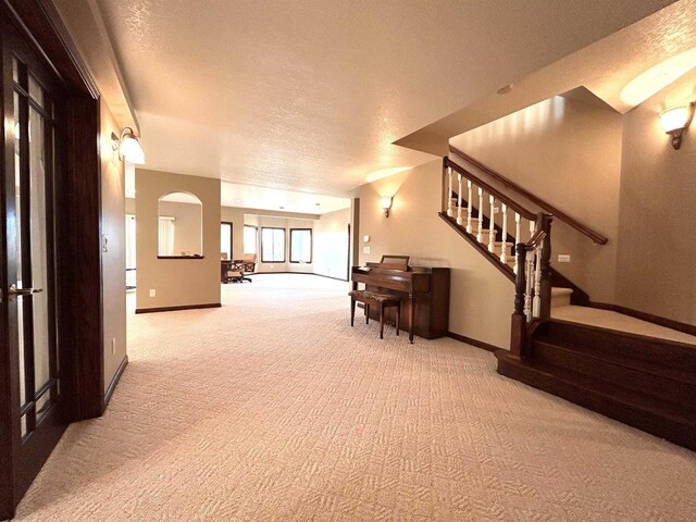 25621 Honeycut Ave, Tomah, WI 54660 - corridor featuring baseboards, a textured ceiling, stairway, and light colored carpet