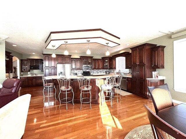 25621 Honeycut Ave, Tomah, WI 54660 - kitchen with light countertops, light wood-style flooring, appliances with stainless steel finishes, arched walkways, and dark brown cabinetry