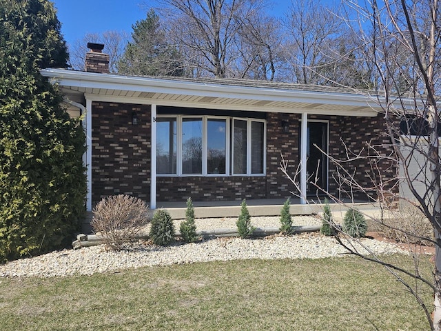 1090 Shabbona Dr, Fontana, WI 53125 - view of home's exterior with brick siding, a chimney, a yard, and a porch