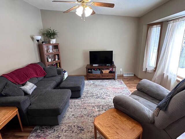 living area featuring a textured ceiling, ceiling fan, visible vents, and wood finished floors