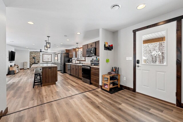W11490 Boat Landing 7 Rd, Athelstane, WI 54104 - kitchen with light countertops, a kitchen island, a kitchen bar, light wood-type flooring, and stainless steel appliances