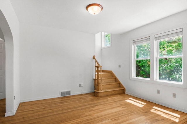 725 Eugenia Ave, Madison, WI 53705 - unfurnished living room featuring arched walkways, light wood-style floors, baseboards, and stairway