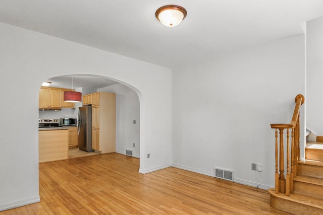 725 Eugenia Ave, Madison, WI 53705 - unfurnished living room with light wood finished floors, arched walkways, stairway, and baseboards