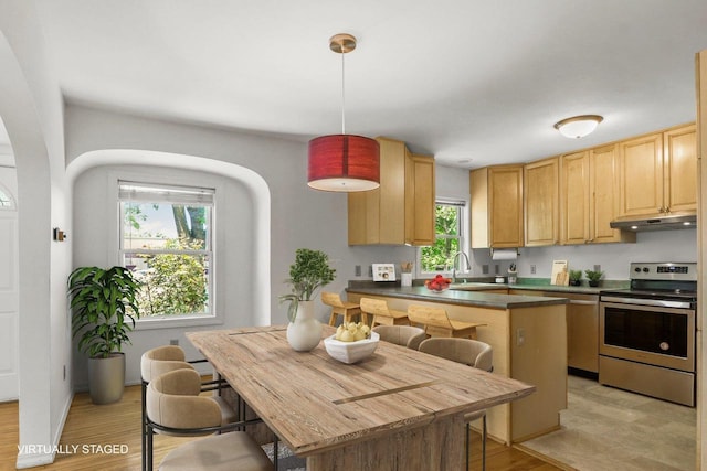 725 Eugenia Ave, Madison, WI 53705 - kitchen with stainless steel electric stove, under cabinet range hood, a breakfast bar, and dark countertops
